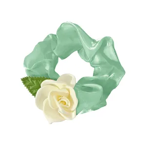 Detail of light green camellia hair scrunchie with a large white rose floral design