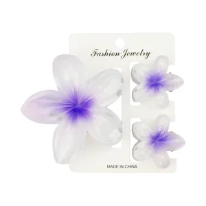 Drei-teiliges Set aus lilafarbenen Plumeria-Haarklammern auf einer weißen Karte