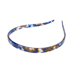Detail view of a narrow tortoise shell headband with blue and amber acetate patterns