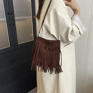Brown vintage bohemian tassel saddle bag in suede leather shown on a shoulder