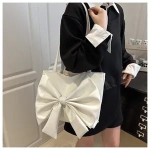 Dettaglio del grande fiocco bianco su una borsa a tracolla capiente dal design chic