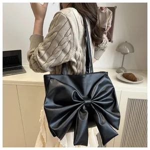 Dettaglio della borsa tote nera con grande fiocco decorativo e pelle sintetica liscia