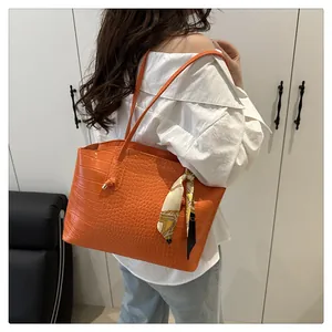 Dettaglio della borsa tote arancione coccodrillo con foulard in seta e tracolla sottile