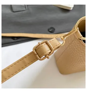 Detail of khaki leather bag featuring woven texture and glossy gold metal buckle