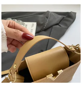 Macro detail of khaki handbag featuring woven texture and gold V-shaped metal buckle