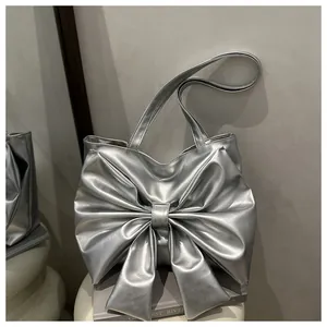 Dettaglio della borsa tote argento metallizzato con grande fiocco e pelle lucida