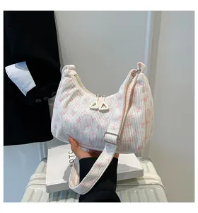 Detail of corduroy hobo bag featuring pink bow prints and dual white zippers on the strap