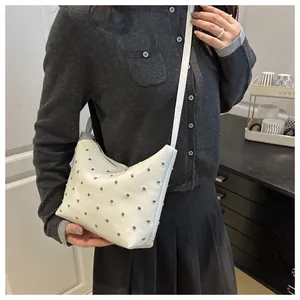 Close-up of white leather shoulder bag with silver rivet studs and a slim strap detail