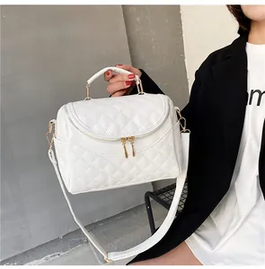 Detail of white quilted cosmetic bag with gold zippers and adjustable shoulder strap
