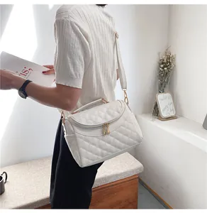 Detail of cream quilted PU leather texture and gold hardware on the shoulder bag