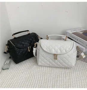 Detailed view of quilted diamond pattern cosmetic bags in black and white with gold hardware