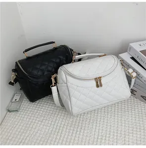 Close-up of quilted leather bags in black and white with gold zippers and top handles