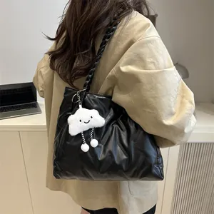 Detail of black quilted tote bag with braided strap and plush cloud charm on a model