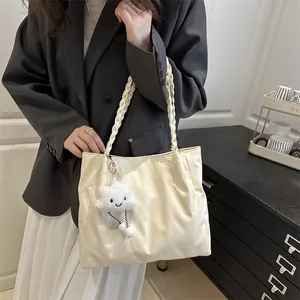 Detail of cream white quilted tote bag with braided handles and cloud plush charm