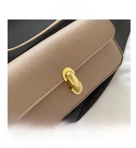Close-up of beige lychee grain leather handbag featuring a golden oval twist lock clasp