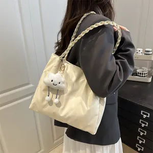 Close-up of beige quilted tote bag with braided rope straps and cute cloud plush charm