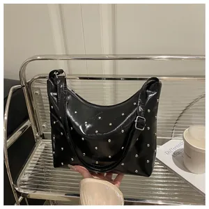 Close-up of black glossy leather shoulder bag with polished silver rivet studs decoration