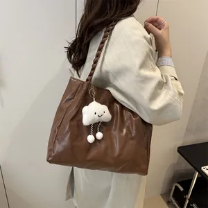 Brown quilted tote bag with chunky woven strap and cloud plush charm detail