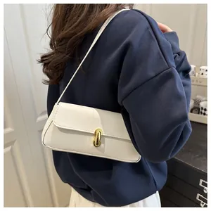 Close-up of white lychee textured underarm bag with a golden metal buckle on a model