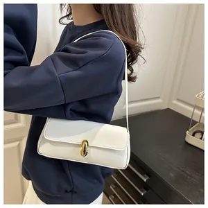 Close-up of white faux leather underarm bag with litchi texture and gold metal buckle