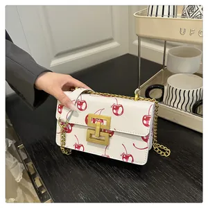 Close-up of white cherry print handbag with golden H-lock and chain strap detail