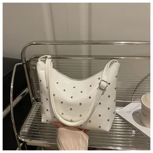 Detail of white PU leather hobo bag featuring silver studs and adjustable strap