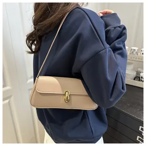 Detailed close-up of beige lychee grain leather handbag with gold oval metal buckle