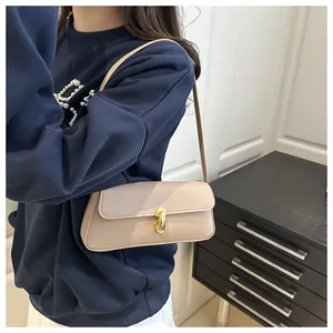 Close-up of beige leather baguette bag with golden metal clasp and slim shoulder strap