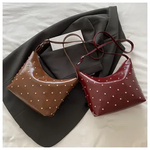 Detailed macro view of retro rivet studded crescent bags in dark brown and wine red
