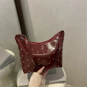 Burgundy faux leather crescent shoulder bag with silver studs and polished finish