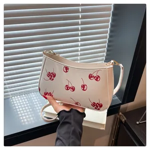 Detail of cherry print on cream shoulder bag with golden metal hook and fine stitching
