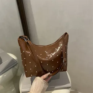 Brown rivet studded faux leather underarm bag with glossy finish and silver hardware
