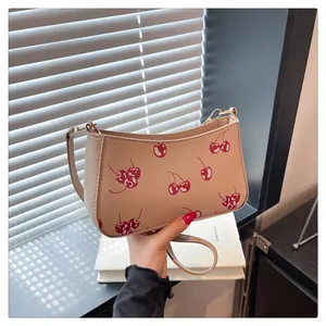 Close-up of vintage cherry print pattern on a light brown leather shoulder bag