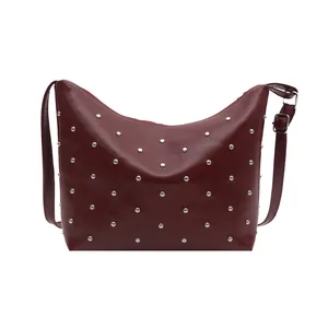Chic burgundy rivet shoulder bag with silver studs and adjustable strap on white background