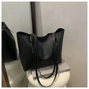 Detail shot of a black leather tote bag featuring a Fashion & Bags logo on a white stool