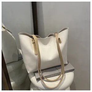 Detail of minimalist cream tote bag showing fine leather texture and golden metal buckle