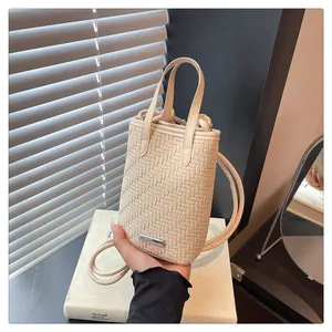 Détail de la texture tressée crème et boucle métallique argentée sur le mini sac bandoulière