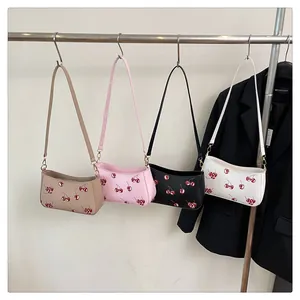 Detail showing cherry print shoulder bags in four colors on a metal display stand