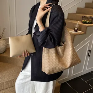 Beige woven leather tote bag and clutch set shown in a stylish professional lifestyle setting