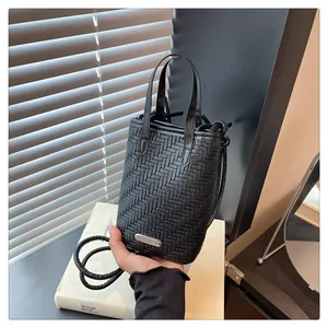 Détail d'un mini sac tressé noir en cuir avec plaque métallique et anse fine