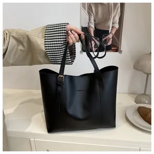 Close-up of black matte leather tote with adjustable gold buckle and fashion text detail