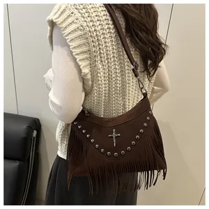 Detail of brown faux suede shoulder bag with fringe, metal studs and cross charm