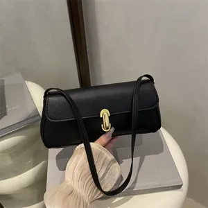 Minimalist black lychee leather shoulder bag with golden lock shown in a home setting