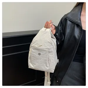 Close-up of cream nylon backpack with crinkled texture and metallic logo on the front