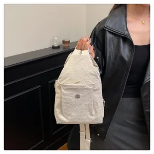 Close-up of stylish cream nylon mini backpack with metal logo on a fashion model