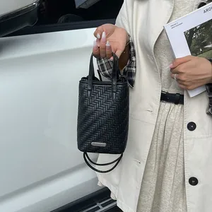 Sac seau tissé noir chic avec détail métallique élégant et bandoulière amovible