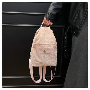 Detail of pink pleated nylon texture and round metal logo on a trendy mini backpack