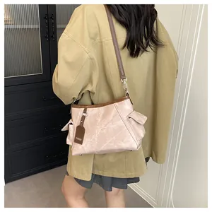 Detailansicht der rosa Schultertasche mit Steintextur, braunem Lederband und Mode-Tag