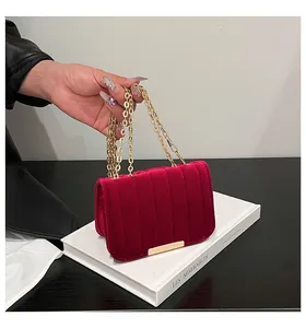 Detailed texture of burgundy velvet crossbody bag with vertical quilting and gold chain