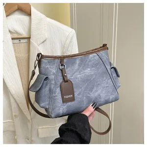 Detail of blue textured shoulder bag featuring brown leather trim and side pockets